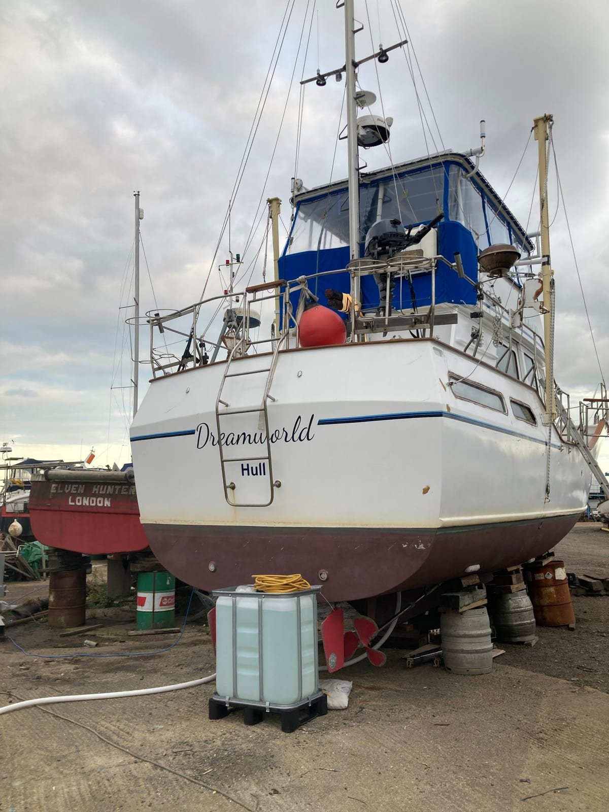 Dreamworld hauled out of the water and propped on stands in a boatyard, her name painted in script across the transom, her propeller and rudder exposed beneath.